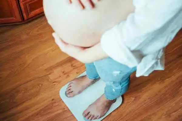 Image of woman weighing herself and experiencing weight gain through pregnancy Littlehampton